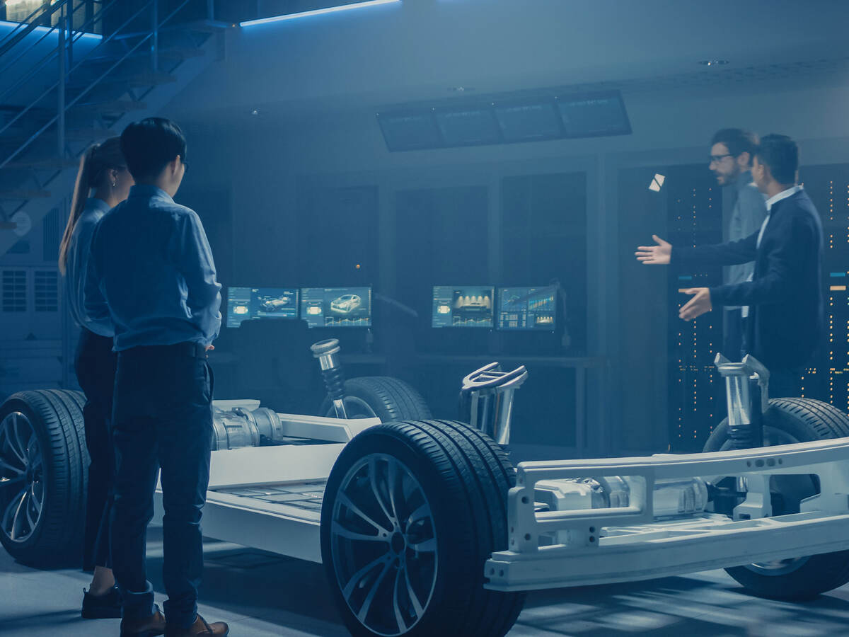 Four people working around a base of an electric car