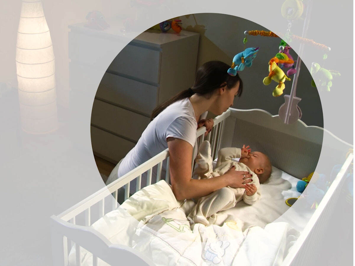A parent putting a child to nap in a crib